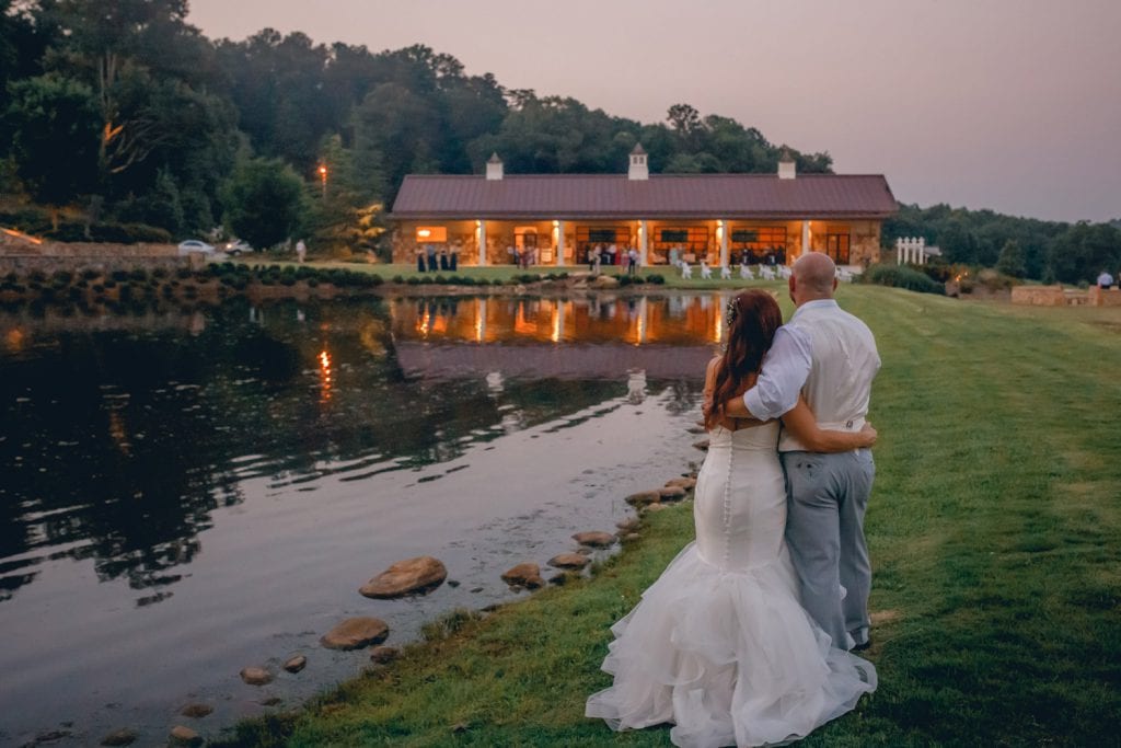 Bride and groom look across the water at wedding venue